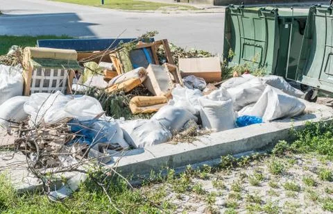 Big plastic dumpster garbage can overflow litter polluting street in the city Stock Photos