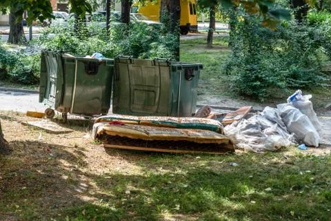 Big plastic dumpster garbage can full overflow litter polluting street in city Stock Photos