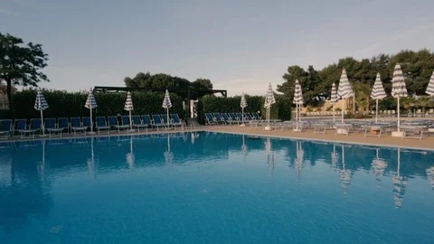 Big pool with closed umbrellas Stock Footage 86487416