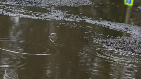 Big puddle with muddy rainwater with bubbles in pothole of asphalt road Stock Footage 194395292