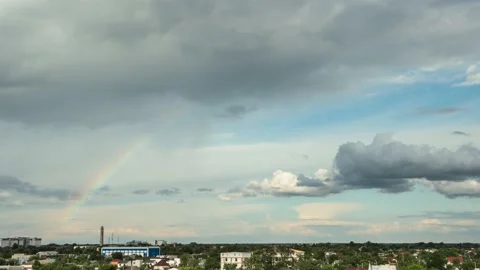 Big rainbow appears in the sky after the rain. Clouds moving fast in a timelapse Stock Footage 202698306