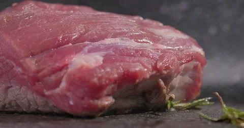 Big raw steak meat beef roasting with rosemary and garlic. Extra close-up. Slow Stock Footage 258377233