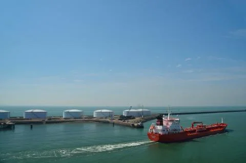 Big red cargo ship in a harbor near the sea Stock Photos