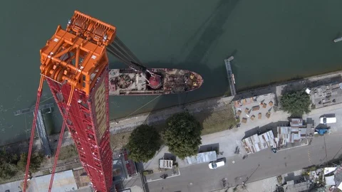 A big red crane preparing an old ship for repairs at the shipyard Stock Footage 120987768
