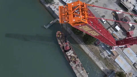 A big red crane preparing an old ship for repairs at the shipyard Stock Footage 120987829