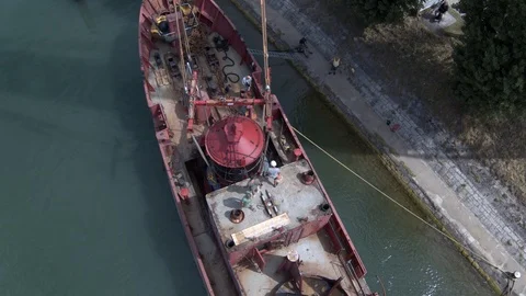 A big red crane preparing an old ship for repairs at the shipyard Stock Footage 120987975