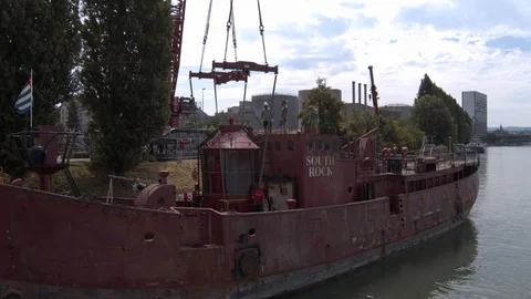 A big red crane preparing an old ship for repairs at the shipyard Stock Footage 120988056