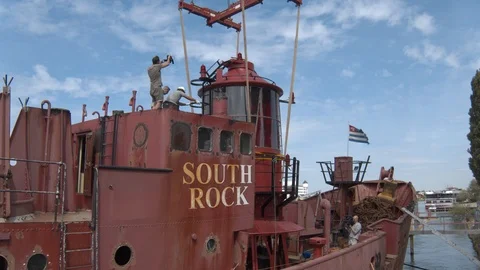 A big red crane preparing an old ship for repairs at the shipyard Stock Footage 120988160