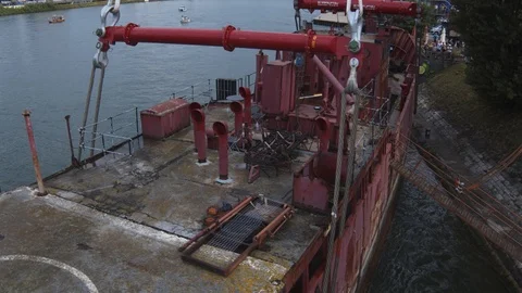A big red crane preparing an old ship for repairs at the shipyard Stock Footage 120990101