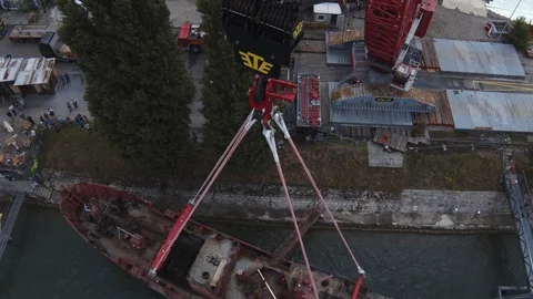 A big red crane preparing an old ship for repairs at the shipyard Stock Footage 120990430