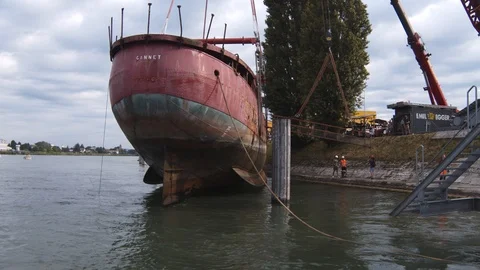 A big red crane preparing an old ship for repairs at the shipyard Stock Footage 120990525