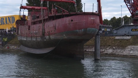 A big red crane preparing an old ship for repairs at the shipyard Stock Footage 120990601