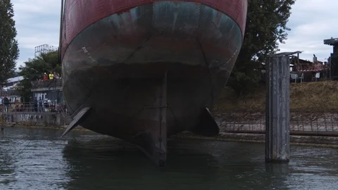 A big red crane preparing an old ship for repairs at the shipyard Video stock 120990696