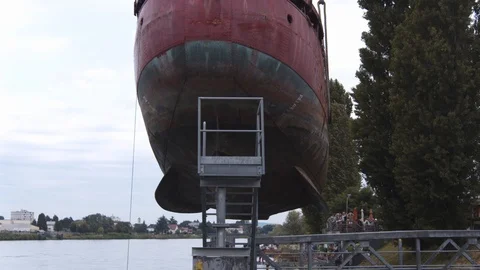 A big red crane preparing an old ship for repairs at the shipyard Stock Footage 120990911