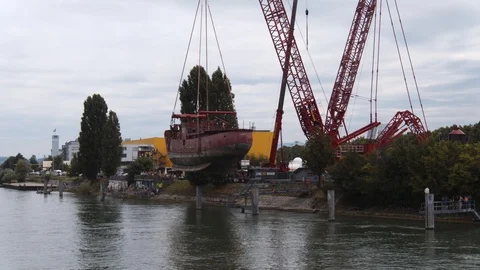 A big red crane preparing an old ship for repairs at the shipyard Stock Footage 120991402