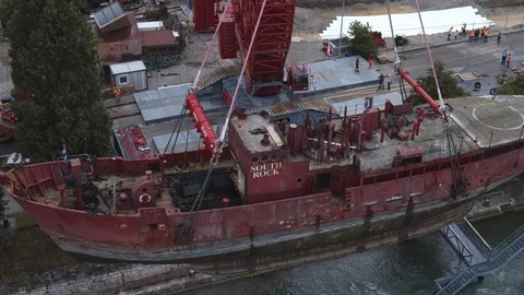 A big red crane preparing an old ship for repairs at the shipyard Stock Footage 120991726