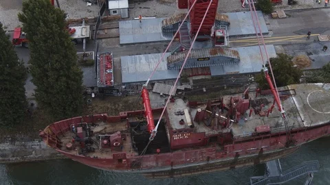 A big red crane preparing an old ship for repairs at the shipyard Stock Footage 120991846