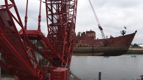 A big red crane preparing an old ship for repairs at the shipyard Stock Footage 120991961