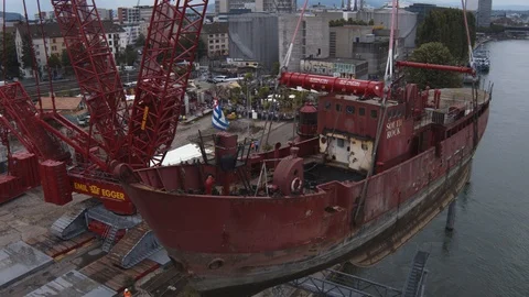 A big red crane preparing an old ship for repairs at the shipyard Stock Footage 120991993