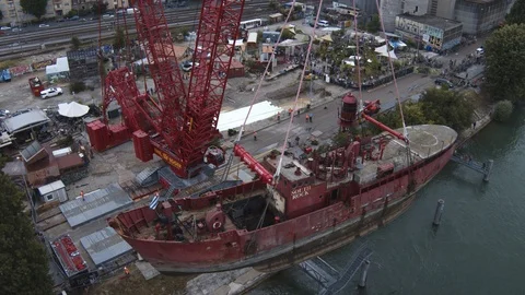 A big red crane preparing an old ship for repairs at the shipyard Stock Footage 120992096