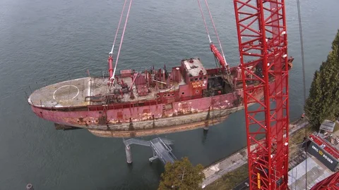 A big red crane preparing an old ship for repairs at the shipyard Stock Footage 120992291