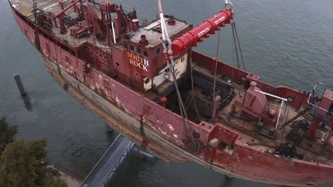A big red crane preparing an old ship for repairs at the shipyard Stock Footage 120992381