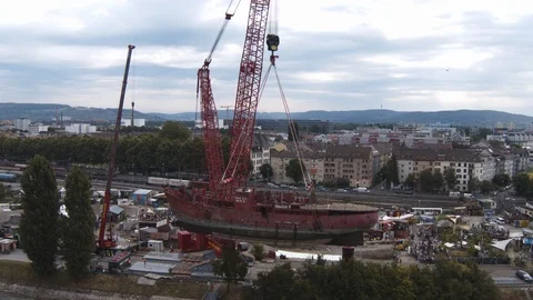 A big red crane preparing an old ship for repairs at the shipyard Stock Footage 120992566