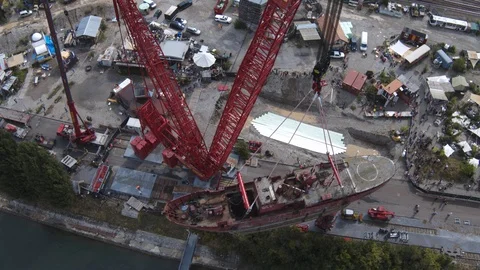 A big red crane preparing an old ship for repairs at the shipyard Stock Footage 120992881