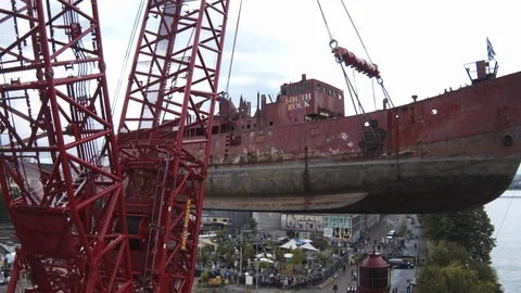 A big red crane preparing an old ship for repairs at the shipyard Stock Footage 120993030