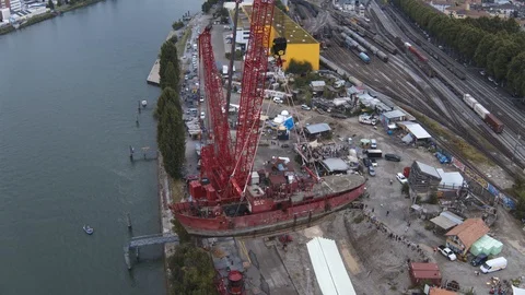A big red crane preparing an old ship for repairs at the shipyard Stock Footage 120993087