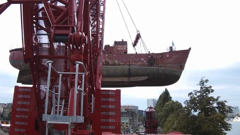 A big red crane preparing an old ship for repairs at the shipyard Video stock 120993164