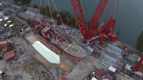A big red crane preparing an old ship for repairs at the shipyard Stock Footage 120993381