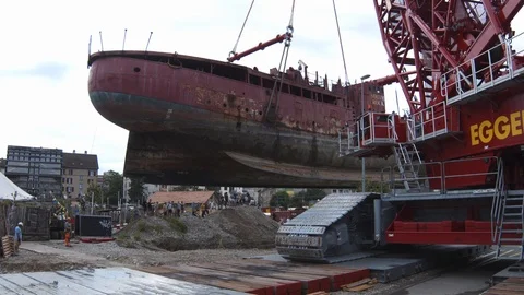 A big red crane preparing an old ship for repairs at the shipyard Stock Footage 120993478
