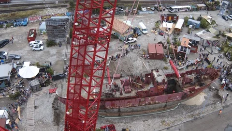 A big red crane preparing an old ship for repairs at the shipyard Stock Footage 120994522
