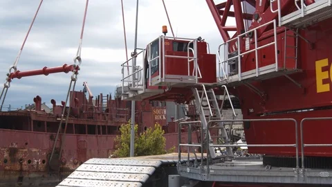 A big red crane preparing an old ship for repairs at the shipyard Stock Footage 120994576