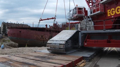 A big red crane preparing an old ship for repairs at the shipyard Stock Footage 120994707