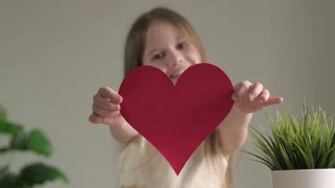 Big red heart close up in hands of little smiling girl on Valentines Day Stock Footage 168552811