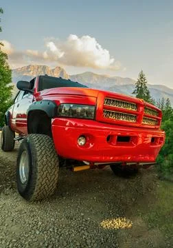 A big red monster truck with dirt tires standing on an off road against mount Stock Photos