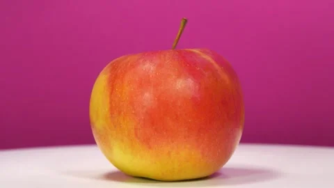 Big red ripe apple rotates on pink backdrop Vídeos de archivo 321194990
