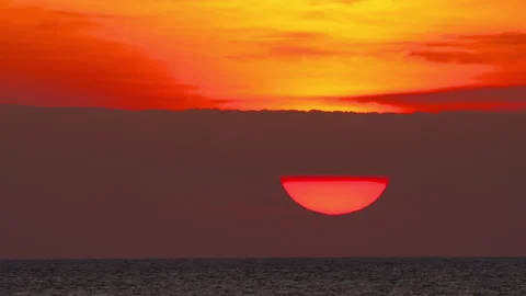 Big red sun setting behind clouds over calm ocean horizon Stock Footage 337158661