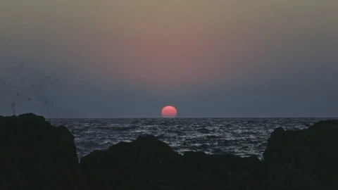 Big red sun setting slowly over the sea or ocean horizon, grey sky with slow Stock Footage 171814671
