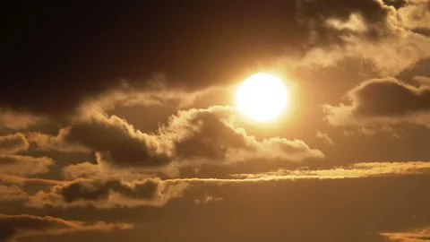 Big Red Sun at Sunset Sits Down and Hides Behind the Clouds Floating in the Sky Stock Footage 104070423