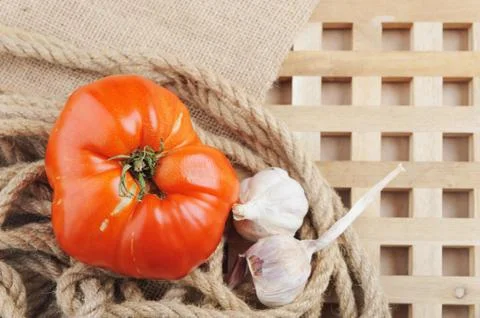 The big red tomato and garlic on beige background. Top view. Stock Photos