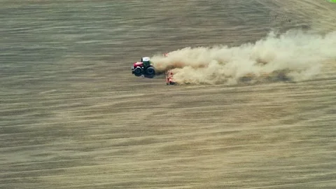 A big red tractor plows the soil Stock Footage 131187596