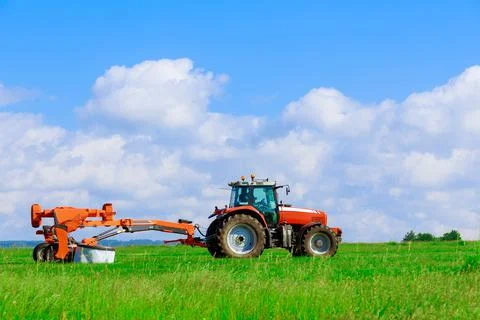Big red tractor with two mowers mows the grass for silage Stock Photos