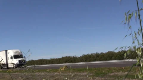 Big rig semi trucks, passing blowing weeds along road Stock Footage 35407969