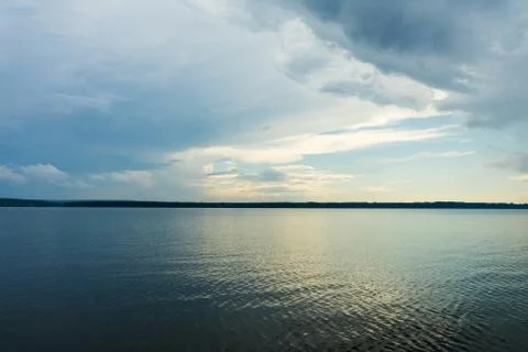 A big river flows under big clouds. Stock Photos