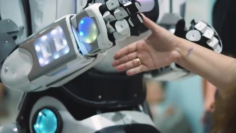 Big robot shaking humans hand and giving high five. Humanoid antropomorf robot. Stock Footage 78669064