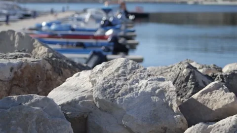 Big rocks at the marina. Through the rocks in the blur you can see motor boats Stock Footage 314982379