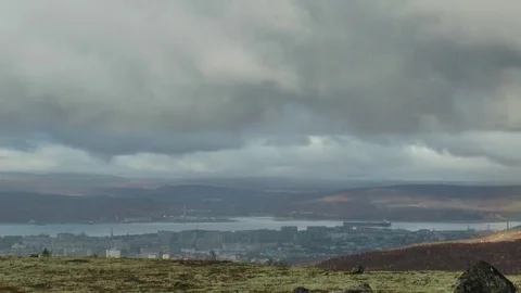 Big rocks in a mossy plain against a river and city in the distance, timelapse. Stock Footage 75419458
